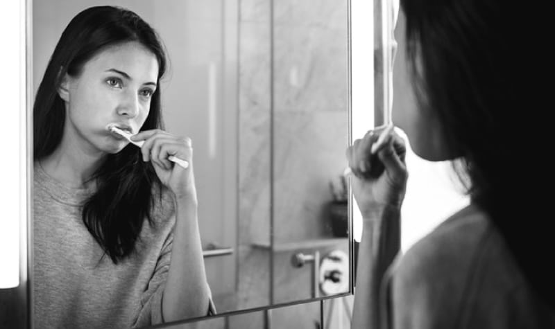 girl looking in the mirror brushing her teeth